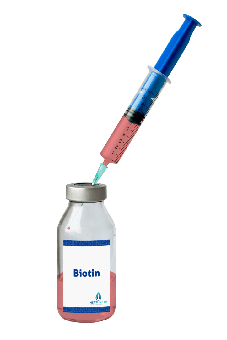 A syringe is drawing a green liquid from a vial labeled "biotin." the background is plain white, highlighting the medical components.