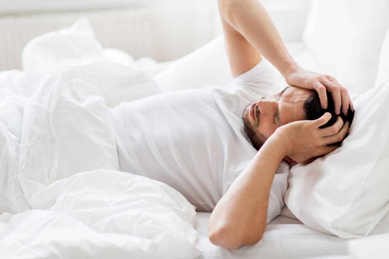 A man laying in bed with his head on the pillow.